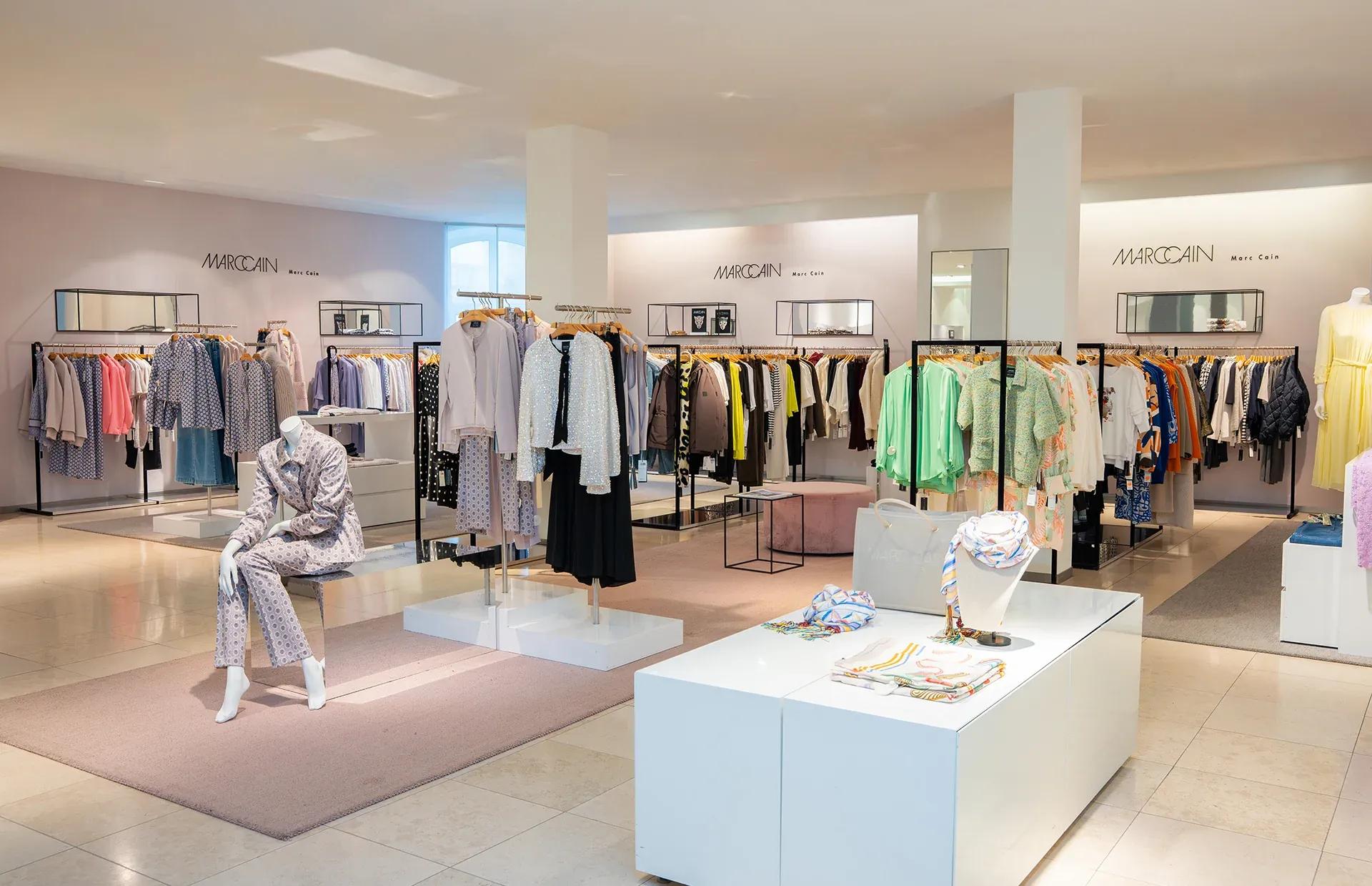 Modern clothing store interior with minimalist racks displaying contemporary apparel and mannequins.