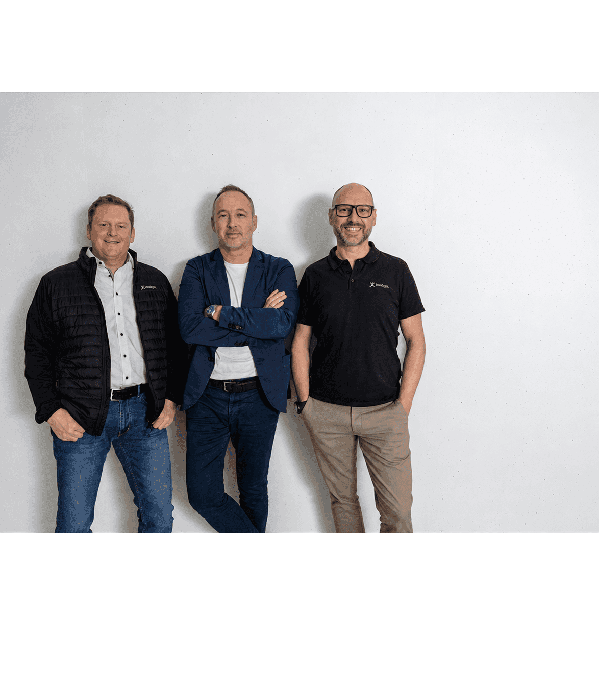 Three professional men standing confidently against a plain white background.